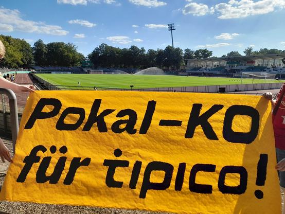 Im Sachs-Stadion in Schweinfurt ist ein orangener Banner mit der Aufschrift "Pokal-KO für tipico!" zu sehen.