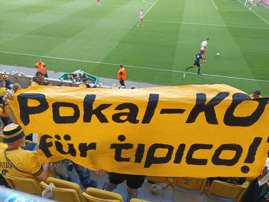 Ein oranger Banner mit der Aufschrift „Pokal-KO für Tipico!” gezeigt von Fans der SG Dynamo Dresden im Pokalspiel gegen den 1. FSV Mainz 05.