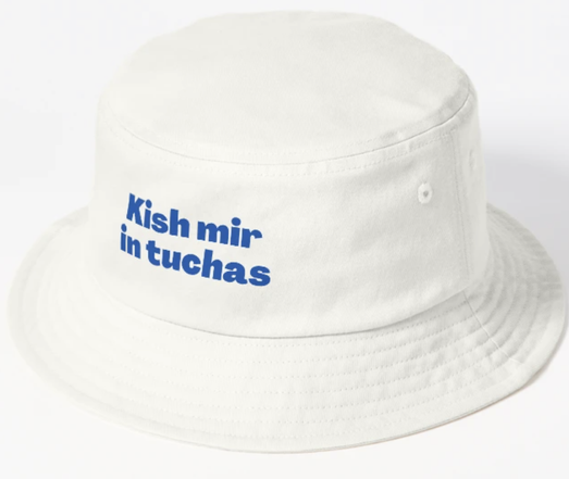 The funny Yiddish saying kish mir in tuchas is shown in blue lettering on a white bucket hat.