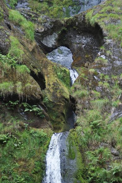 Further down the waterfall, the water passes through and natural arch in the rock.