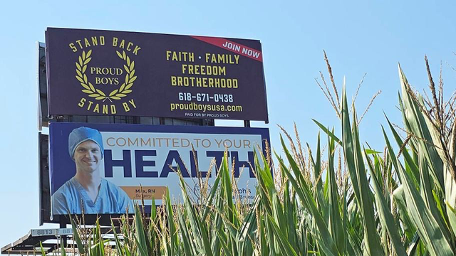 Billboard in a corn field reading: Proud Boys - Stand Back, Stand by. Join now. FAITH • FAMILY JOIN NOW FREEDOM BROTHERHOOD 618-671-0438 proudboysusa.com PAID FOR BY PROUD BOYS