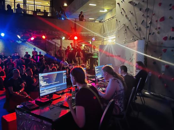 Copper Showdown, in action at evoke. In the foreground of the picture there are four competitors working on their effects. The hall is packed with people watching on both levels of the hall