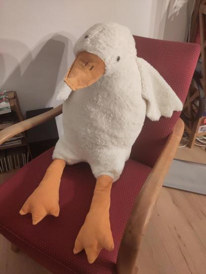 A giant goose plushie on an armchair.