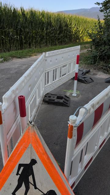 Nahaufnahme der Baustelle. Mehrere Baken sind eng um zwei frisch platzierte Poller herum aufgestellt worden. An der Spitze ist ein Baustellenwarnschild zu sehen.
