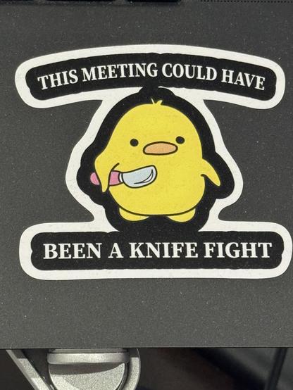 Laptop sticker of a fat cartoon duckling holding a cartoon knife, titled, “This meeting could have been a knife fight”