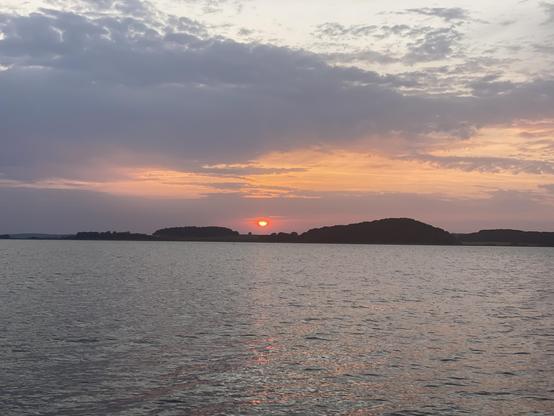 Die Sonne geht hinter einer Landspitze unter.