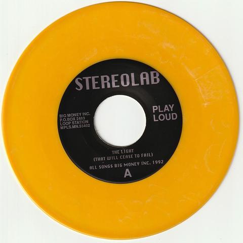 Photo du 7" de Stereolab intitulé "The light that will cease to fail". Le vinyle est orange (transparent ce qui ne se voit pas sur la photo), le label est noir.