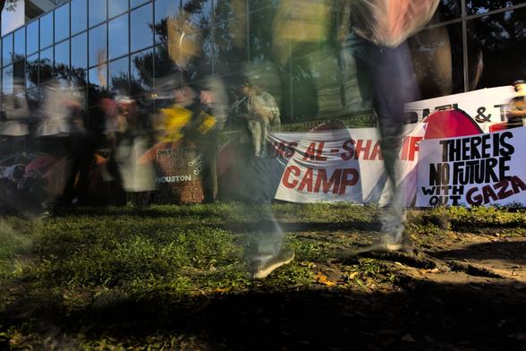 A slow shutter speed shot with the name of the encampment, Anas Al-Sharif Camp, behind the light blur of moving legs