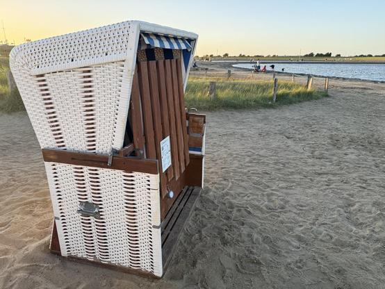 Verriegelter weißer Strandkorb steht am Sandstrand an der Nordseeküste von Büsum.