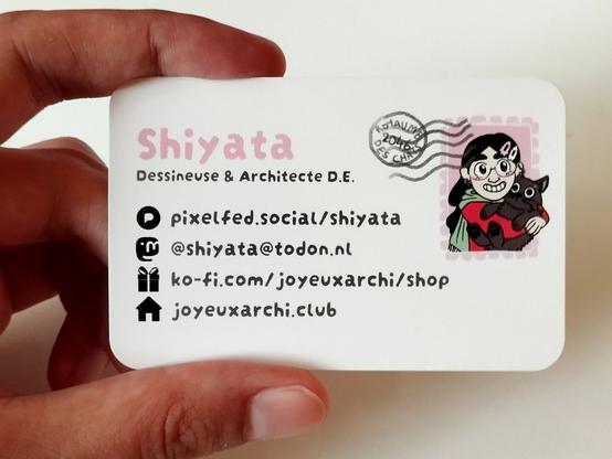 Photo du recto de la carte de visite. A droite il y a un timbre avec un dessin de mon chat et moi, et un tampon de la poste avec écrit "2046 - Le royaume des chats".

A gauche il y a écrit en rose et en grand "Shiyata".
En dessous il y a écrit en anthracite "Dessineuse et architecte D.E." (D.E. ça veut dire Diplomée d'Etat)

Après il y a les logos de réseaux sociaux et les URL ou @ :
Pixelfed : pixelfed.social/shiyata
Mastodon : @shiyata@todon.nl
Boutique : ko-Fi.com/joyeuxarchi/shop
Site internet : joyeuxarchi.club