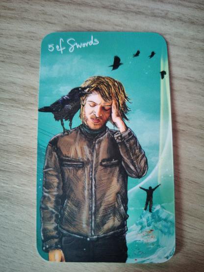 Small tarot card, a man rubs his head with one hand and grimaces whilst a crow sits on his other shoulder. 4 crows fly away in the background and a silhouette figure in the distance raises arms in triumph.