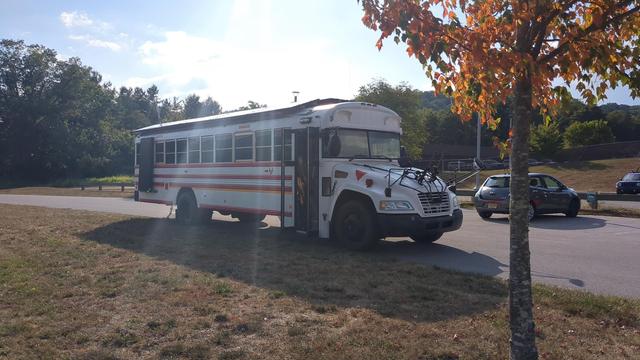 The Vulpibus from another angle, showing the passenger door side. A tree in the foreground is suffering in the heat.