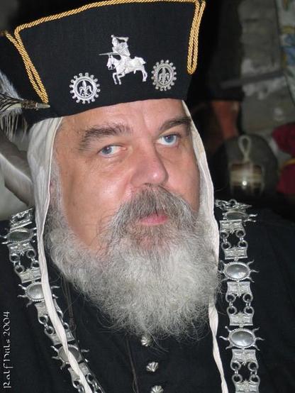 Farbportrait eines älteren Mannes mit weißem Vollbart in vornehmer historischer Kostümierung.