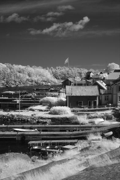 Black and white, infrared photography: houses and boats dotting the Sandhamn shore looking out to Telegrafholmen