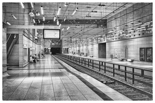 Strassenbahnhaltestelle unter der Stadtmitte, zwei Bahnsteige, zwei Gleise mittig, abgesenkte Bahnsteigkanten, viele kleine längliche Leuchtkörper an der Decke,