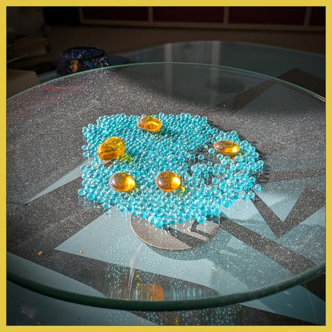 small blue beads en some large yellow beads in a glassbowl. The bright sunlight reveales the dust.