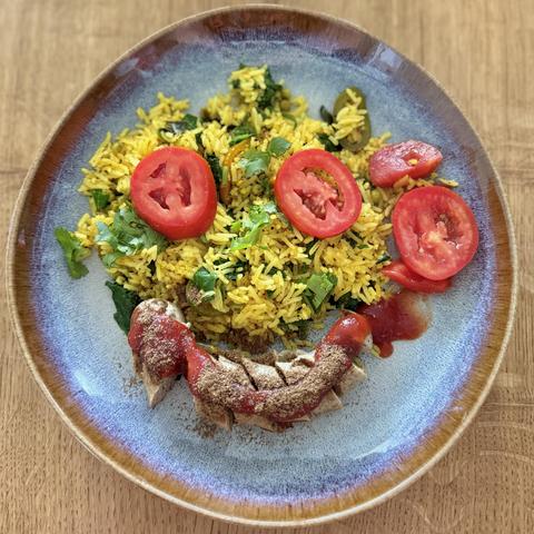 Tomatoes and sausages arranged so that we have a very happy yellow rice face 😀