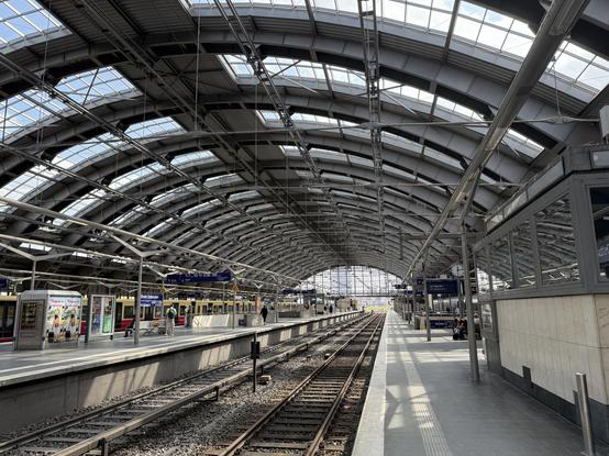 A view along the tracks that are covered by the lovely rounded steel frame roof. Ample of light is coming in through glass panes.