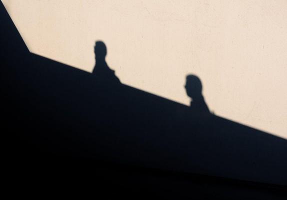 The scene is half black and half lit by the sun. The silhouettes of the two people intersect between the bright and dark areas, almost like two puzzle pieces joining together.