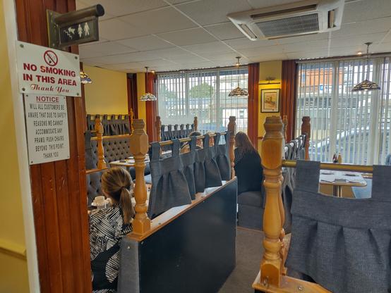 Another photo from a different angle of some traditional looking booths inside a fish chip restaurant. Each booth is made of wood surrounds with blue heavy material drapes separating each booth
