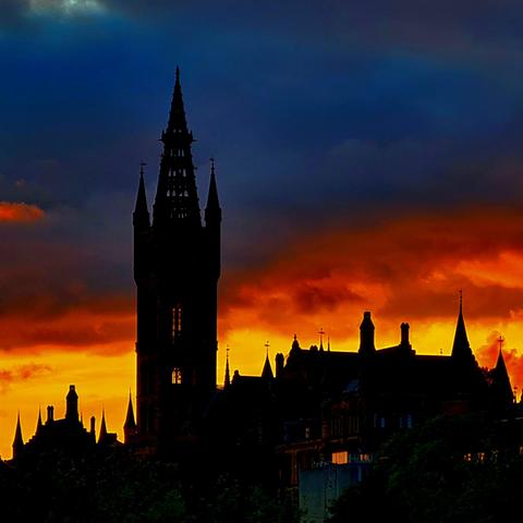 A gothic university building silhouetted against a sunset.