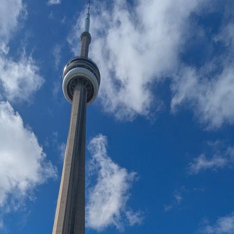 CN Tower viewed from below with blue sky and fluffy clouds