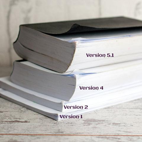 Buchstapel meiner gedruckten Manuskripte. Beschriftung: "Version 1, Version 2, Version 3, Version 4". Jedes Buch ist dicker als der Vorgänger.