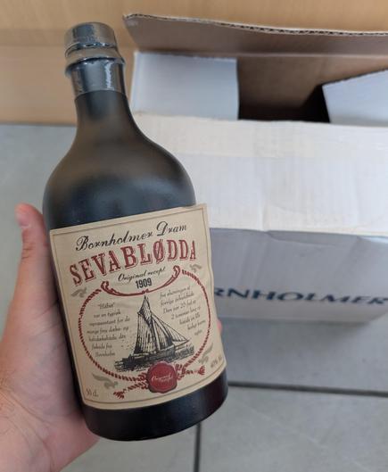 A hand holding a Sevablødda bottle with the Bornholmer box in the background