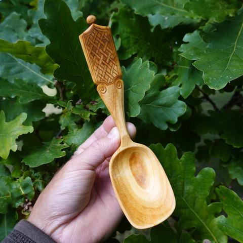 Wooden spoon held with leaves in background