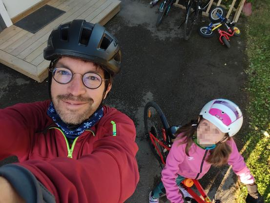 An man and a child in their bikes smiling at the camera.