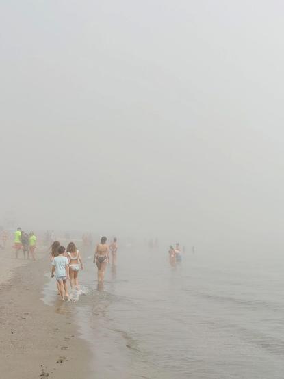 Gente en la playa de Torremolinos. Hay una gran nube baja que hace que las figuras de las personas aparezcan borrosas.