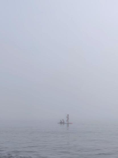 Tres personas haciendo paddle surf en la playa de Torremolinos. Hay una gran nube baja que hace que las figuras de las personas aparezcan borrosas.