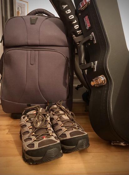 Souliers de randonnées, petite valise, étui à cerf-volant et étui à ukulélé, prêts à partir.