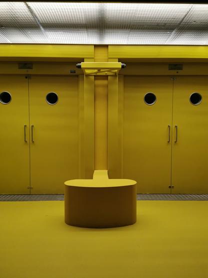 A vibrant yellow interior featuring a round bench and circular door windows.