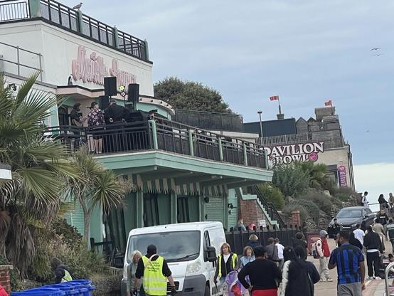 Beachfront cafe with balcony and performers at one end.