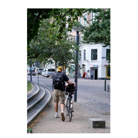 Vater schiebt Fahrrad mit schlafendem Kind auf einem Fahrrad