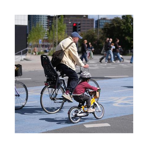 Auf dem beschriebenen Radweg radeln Vater und Kind nebeneinander, das Kind dürfte in jungen bis mittleren Kindergartenalter sein.