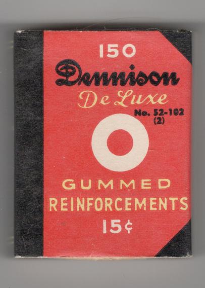 A vintage box of Dennison De Luxe Gummed Reinforcements. Box is approx. 1.75 by 2.25 by .75 inches, designed to resemble a tiny book. It is printed in red, black and yellow.