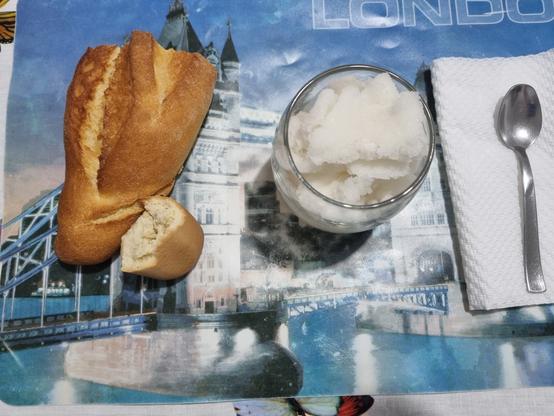 Bicchiere con granita al limone, pane e cucchiaino su un tovagliolo