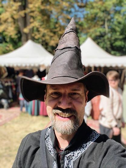 Ich in schwarzen Klamotten und mit neuem Magierhut bei Sonnenschein auf dem MPS in Speyer