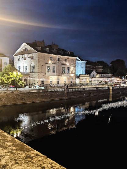 Hotel at night, its lights reflected on the river