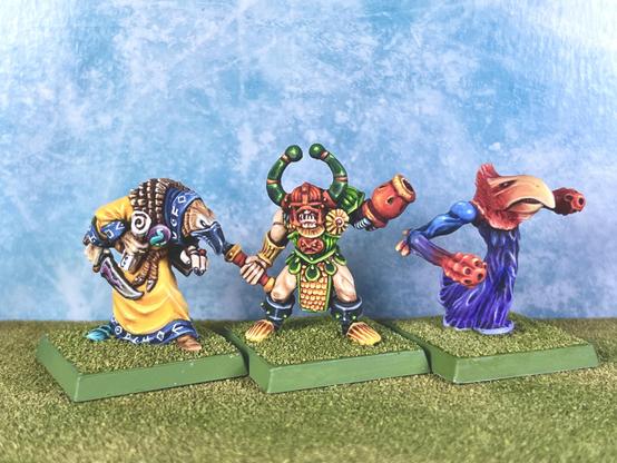 Tzeentch bird-headed sorcerer with bright yellow robes and 3 arms, a Chaos Champion with green & Yellow armour, a battle axe and a flamer arm, and a Blue demon called “flamer of tzeentch”, half mushroom half bird, all murderbird.