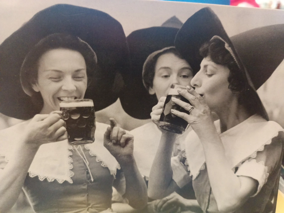 Three ladies in Netherlands drinking a frothy beer big hats