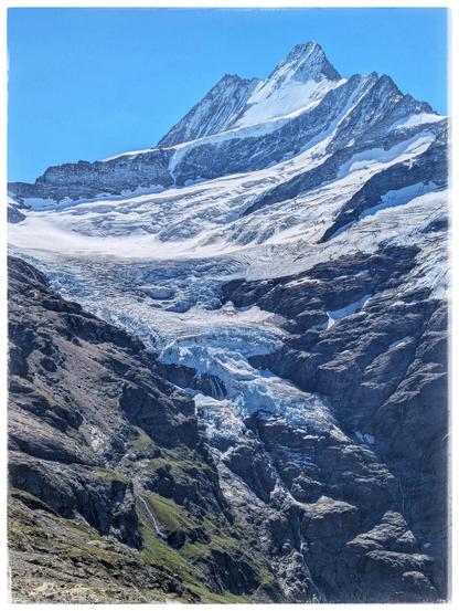 A mountain, covered in snow and a glacier reaching down into a valley.