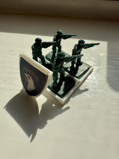 A unit of four allied Memoir 44 soldiers on a 3D printer holder. It has a mount for the unit symbol at the rear.