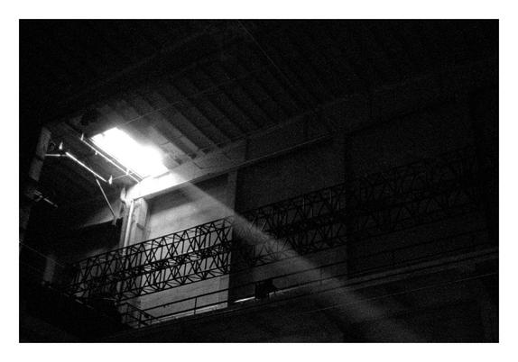 Beam of light entering through a high window in a dark industrial building interior with metal railings