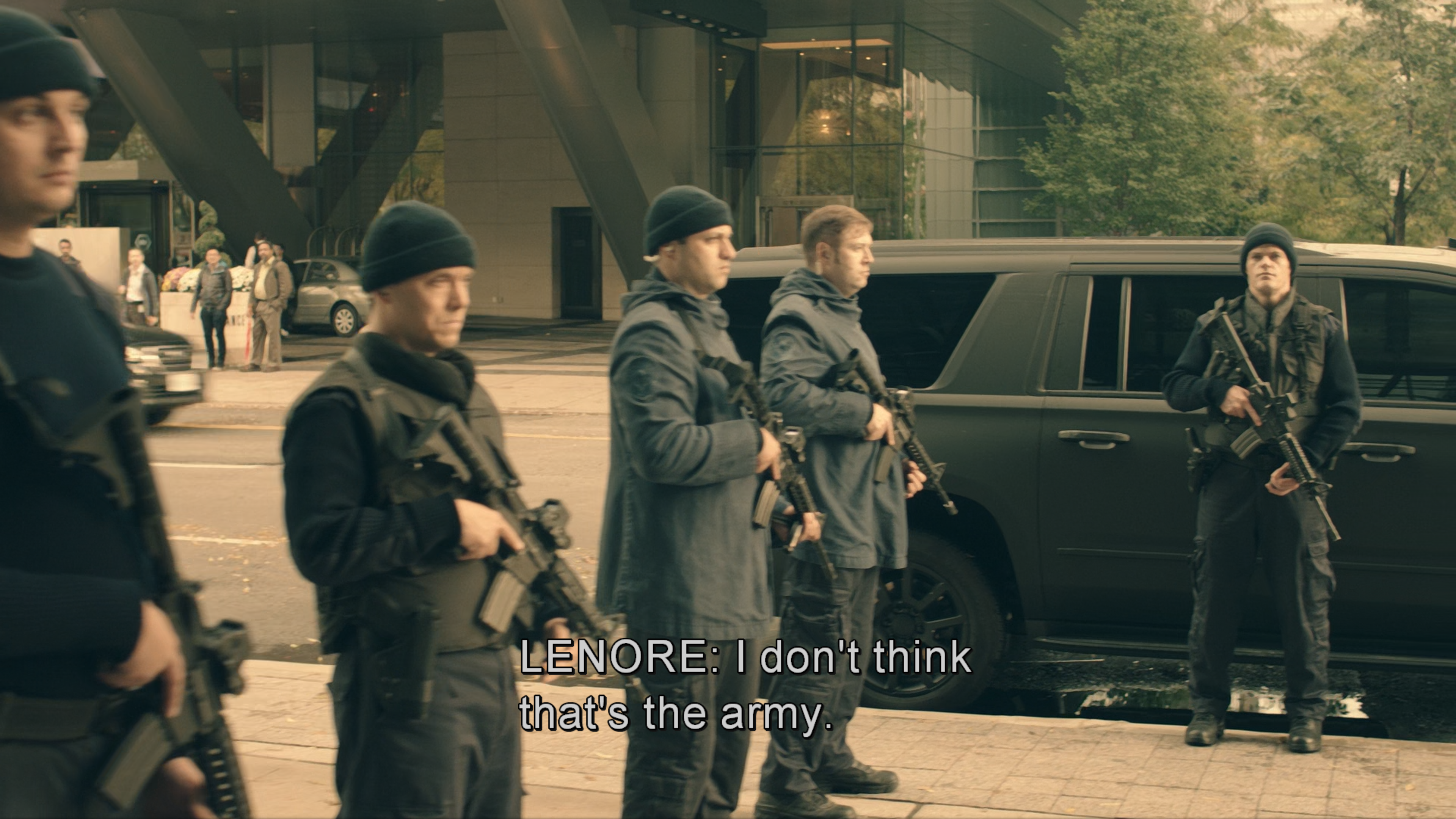 Screenshot from The Handmaid's Tale TV series. Armed soldiers in dark tactical uniforms stand in formation next to the office building, holding assault rifles positioned near a black SUV. Lenore responds in the subtitle "I don't think that's the army" as the newly unemployed women observe these troops that are enforcing the regime's new laws.