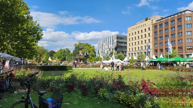 Zu sehen ist ein kleiner Ausschnitt der Königsallee während des Gourmet Festivals. Viele kleine weiße Zelte füllen die Landschaft und bieten den zahlreichen Besucher*innen die verschiedensten Speisen & Getränke an.