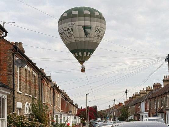 A hot air balloon being guided in an emergency landing on Bower Street, Bedford on 23 August 2025. Image: Emma Firman
There are at least 15 telephone wires stretching across the street from a single telephone pole. This means the telephone wires to the houses on the opposite side of the street like bicycle wheel spokes would look from one half of the bicycle wheel.
From the photo it's not possible to see how the large balloon caring people in the basket below the balloon, descended between the wires.