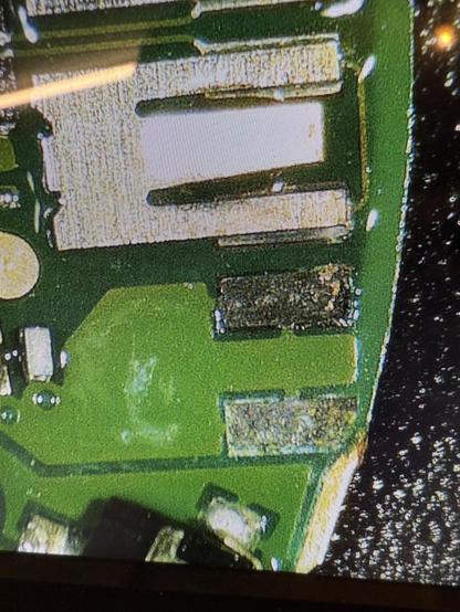 A close-up view of a circuit board featuring various electronic components, including capacitors and resistors, on a green substrate. The image shows details of the circuit layout and soldered connections.